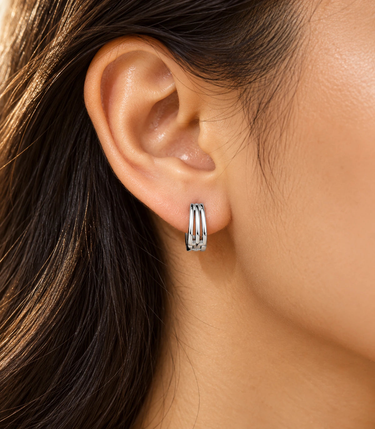 JIMIKI Silver Triple Open Rail Huggie Hoop Earrings, worn in warm editorial lighting #color_silver