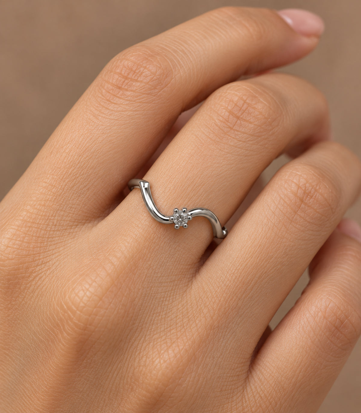 Close view of the wave ring and single clear stone worn on a finger