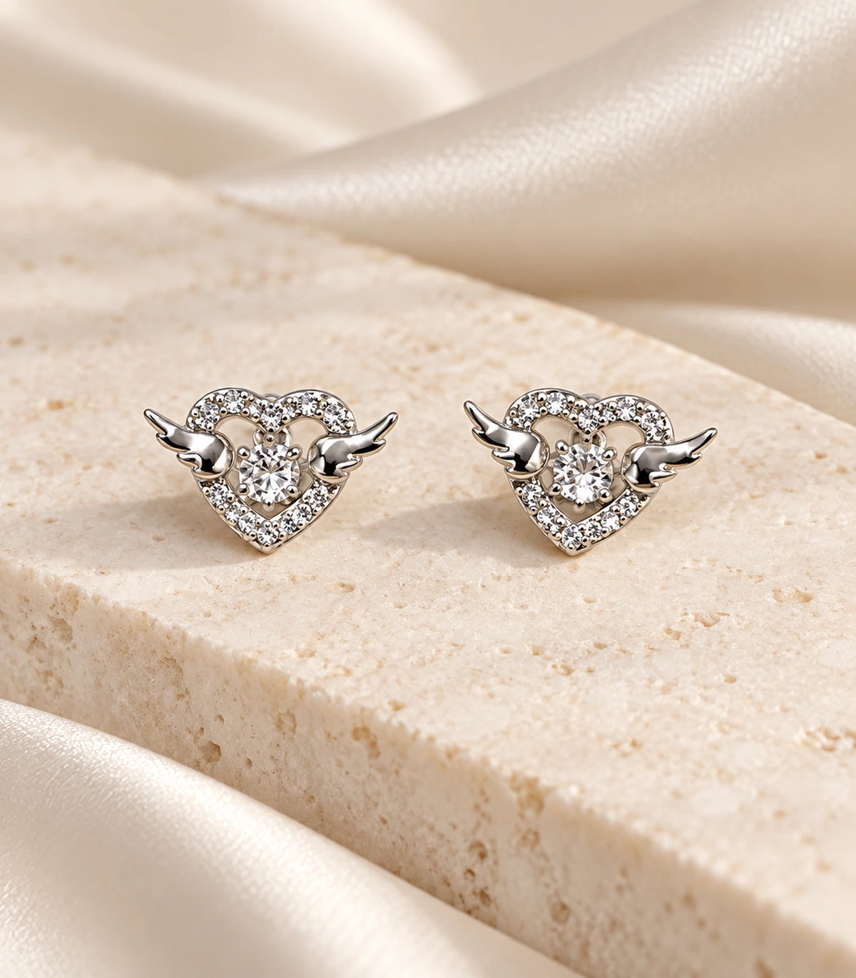 JIMIKI Winged Heart Crystal Stud Earrings in Silver — editorial flat lay #color_silver