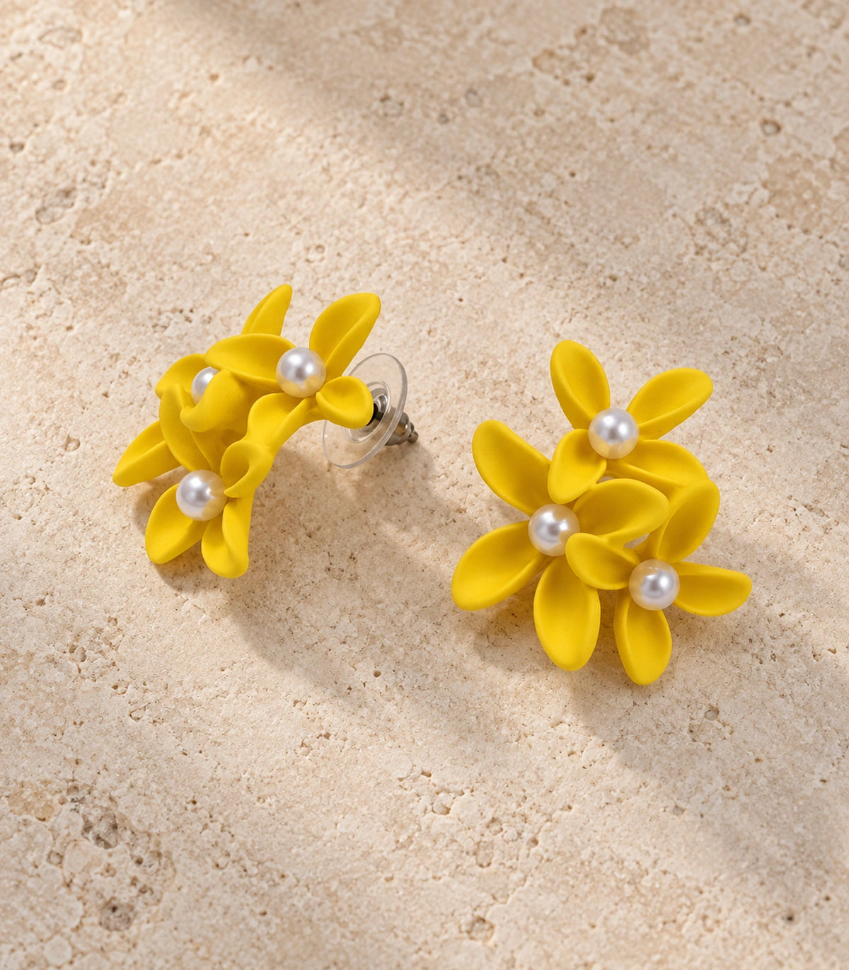 JIMIKI Yellow cascading floral cluster stud earrings, matching pair styled on a light textured surface #color_yellow